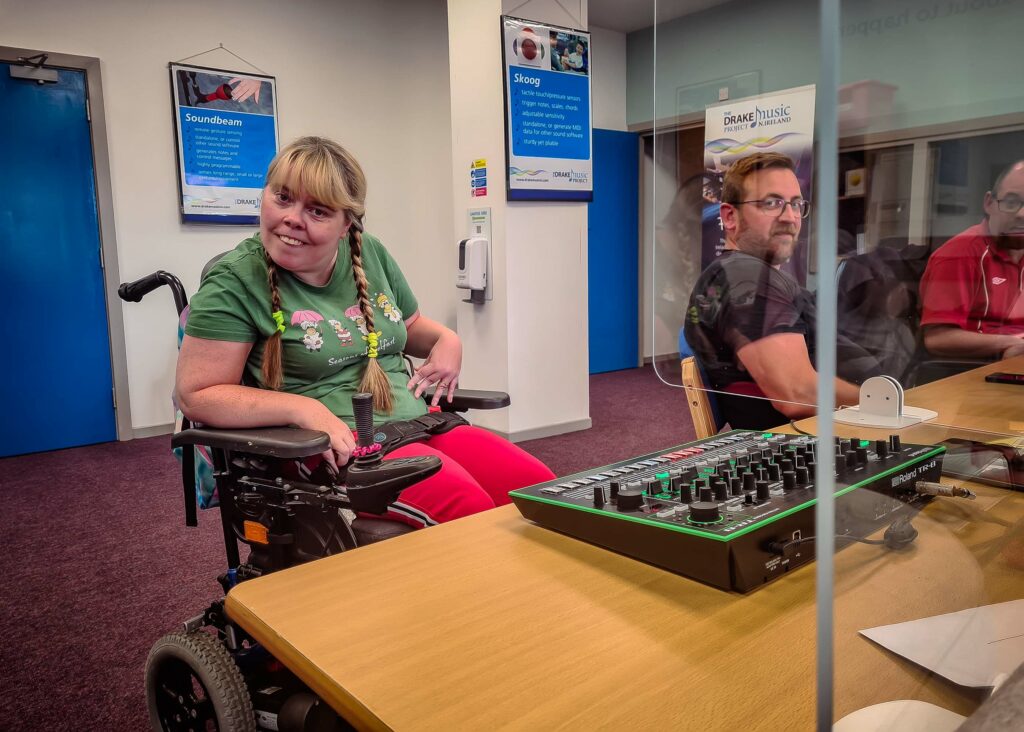 Musician Marylouise smiles at camera, along with the musician Tim and his carer Chris during the Wired Ensemble session in Belfast.