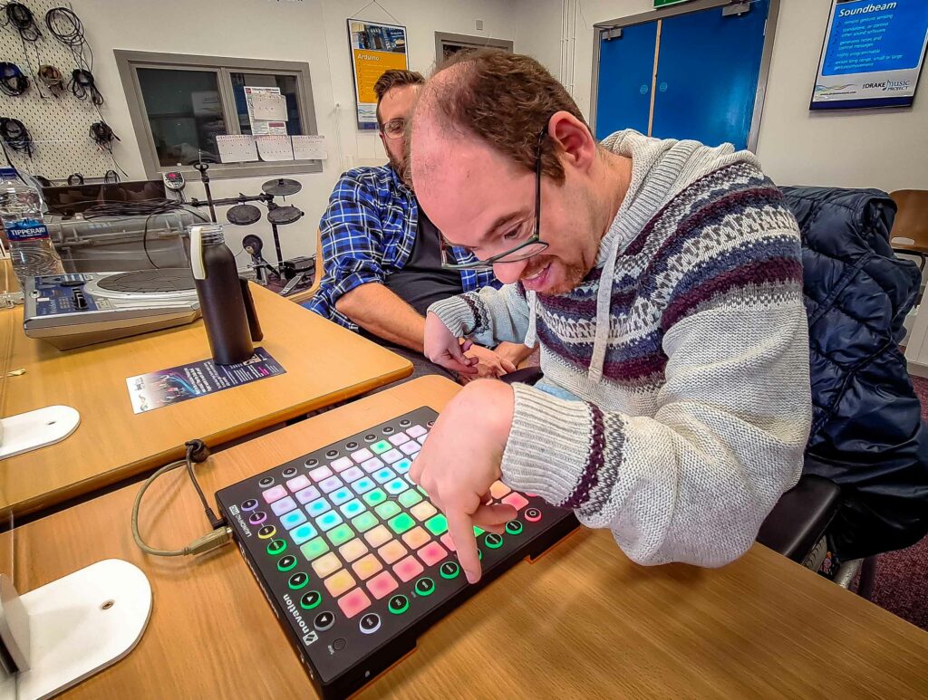 Musician and composer Tim* smiles while playing the Launchpad Pro during the 'Wired Ensemble' session at Drake Music’s studios in Belfast.